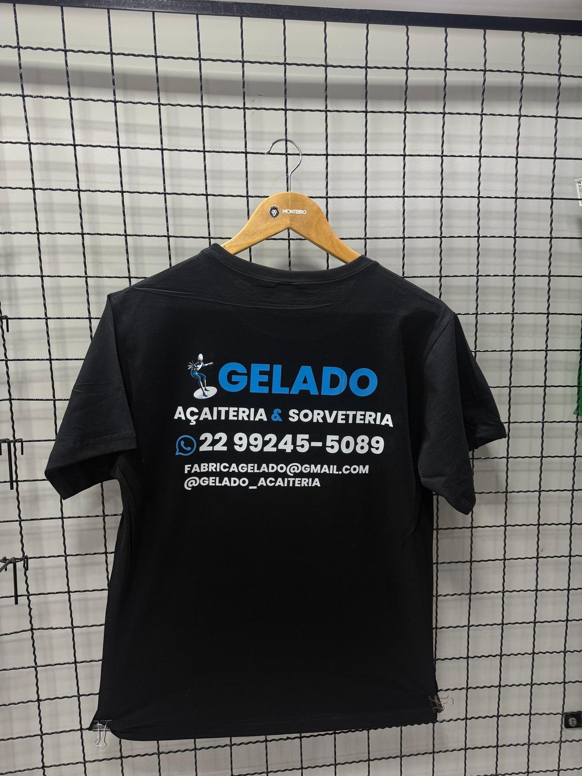 Camiseta preta com logo e contatos de uma açaiteria nas costas