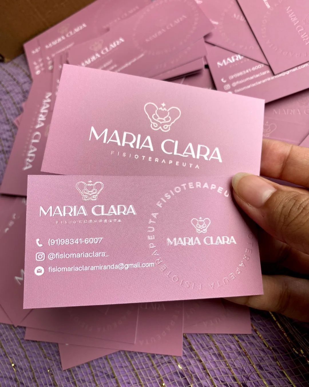 Cartões de visita rosa de fisioterapeuta espalhados sobre a mesa
